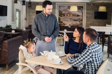 Restoran ve tatil kavramı - kafe mutlu aile için menü veren garson