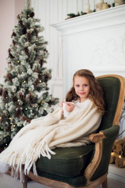 Küçük kız evde sabah Noel ağacı yakınındaki süt içme