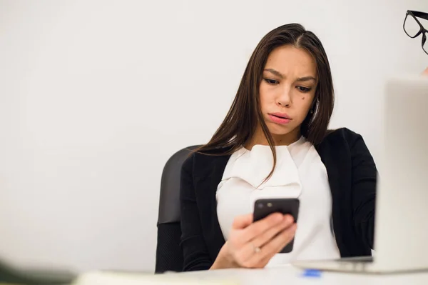 Znudzona kobieta o jej biurko typimg wiadomość na telefon komórkowy — Zdjęcie stockowe