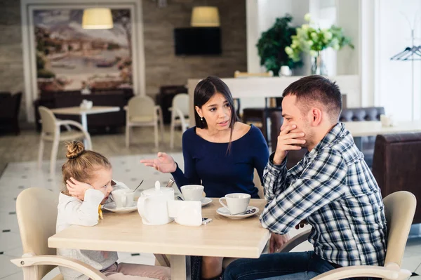 Pár boje před dítě v kavárně nebo restauraci. — Stock fotografie