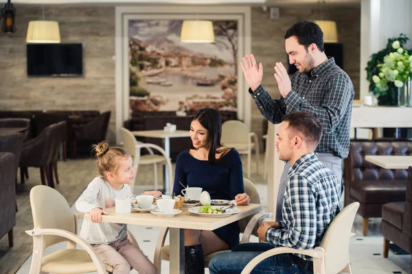 家庭、 亲子关系、 技术、 人的概念 — — 快乐的妈妈，爸爸和小女孩吃饭问服务员要拍照的智能手机 — 图库照片