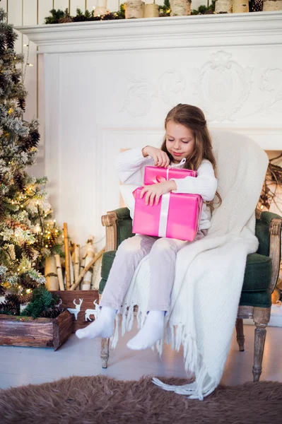 Gelukkig meisje Kerstcadeaus te openen bij een ingerichte open haard in de gezellige lichte woonkamer op Xmas eve — Stockfoto