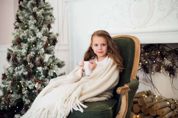 Meisje consumptiemelk in de buurt van de kerstboom in ochtend thuis — Stockfoto