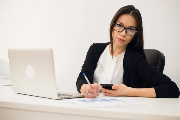 Portret van zakenvrouw met laptop schrijft op een document in haar kantoor — Stockfoto