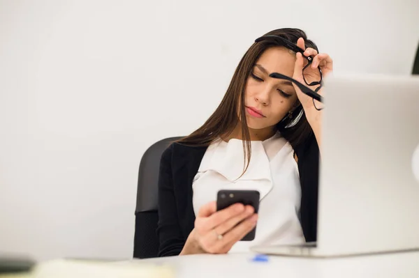 Mujer aburrida en su escritorio typimg mensaje en el teléfono móvil — Foto de Stock