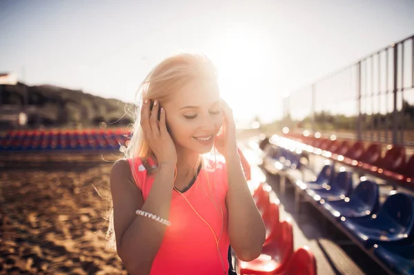 Sport na zewnątrz Fotografia piękne Młoda kobieta blonde w różowym kolorze kolorowe, słuchanie muzyki na słuchawkach przy plaży — Zdjęcie stockowe