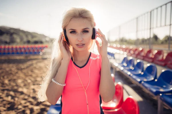 야외 사진 해변으로 헤드폰에서 음악을 듣고 분홍색 화려한 옷에 아름 다운 젊은 금발 여자의 스포츠 — 스톡 사진