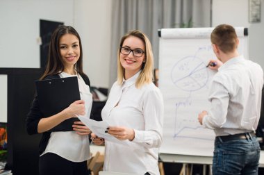 Konuşmayı adam meslektaşım iş stratejisi üzerinde flip grafik çizim sırasında iki güzel Ofis çalışanları.