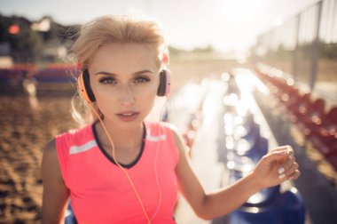 Plaj voleybolu koltuk üzerinde poz kulaklık ile genç güzel kadın