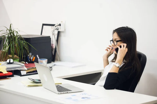 Jovem empresária sentada e conversando ao telefone — Fotografia de Stock