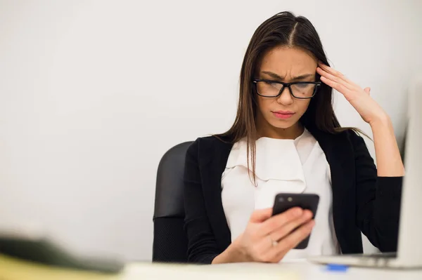 Znudzona kobieta o jej biurko typimg wiadomość na telefon komórkowy — Zdjęcie stockowe