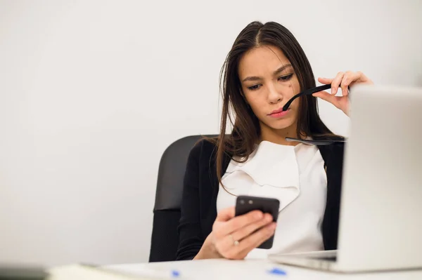 Empresária entusiasmada ganhando após a realização ler telefone inteligente sentado em um desktop no escritório — Fotografia de Stock