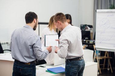 Dizüstü bilgisayar açık plan modern ofis çevresinde toplanan bir ekip olarak çalışma dört genç iş adamları