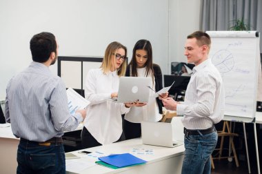 Toplantı ve dizüstü bilgisayarlar kullanarak evraklarla tartışılması sırasında ofisinde oturan genç iş adamları