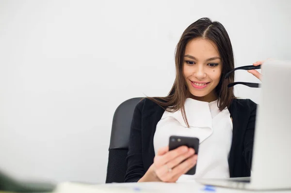 Empresária entusiasmada ganhando após a realização ler telefone inteligente sentado em um desktop no escritório — Fotografia de Stock
