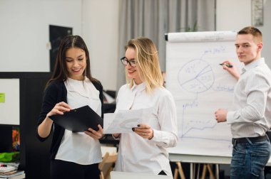 Konuşmayı adam meslektaşım iş stratejisi üzerinde flip grafik çizim sırasında iki güzel Ofis çalışanları.