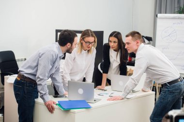 Toplantı ve dizüstü bilgisayarlar kullanarak evraklarla tartışılması sırasında ofisinde oturan genç iş adamları