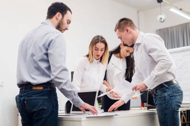 Toplantı ve dizüstü bilgisayarlar kullanarak evraklarla tartışılması sırasında ofisinde oturan genç iş adamları