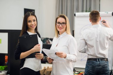 Konuşmayı adam meslektaşım iş stratejisi üzerinde flip grafik çizim sırasında iki güzel Ofis çalışanları.