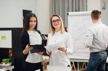 Konuşmayı adam meslektaşım iş stratejisi üzerinde flip grafik çizim sırasında iki güzel Ofis çalışanları.