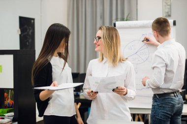 Konuşmayı adam meslektaşım iş stratejisi üzerinde flip grafik çizim sırasında iki güzel Ofis çalışanları.