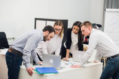 Toplantı ve dizüstü bilgisayarlar kullanarak evraklarla tartışılması sırasında ofisinde oturan genç iş adamları