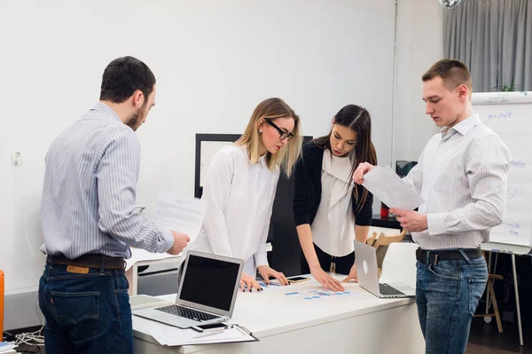 Toplantı ve dizüstü bilgisayarlar kullanarak evraklarla tartışılması sırasında ofisinde oturan genç iş adamları