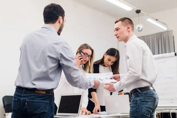 Toplantı ve dizüstü bilgisayarlar kullanarak evraklarla tartışılması sırasında ofisinde oturan genç iş adamları