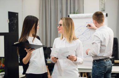 Konuşmayı adam meslektaşım iş stratejisi üzerinde flip grafik çizim sırasında iki güzel Ofis çalışanları.