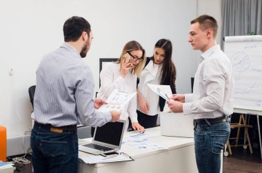Toplantı ve dizüstü bilgisayarlar kullanarak evraklarla tartışılması sırasında ofisinde oturan genç iş adamları