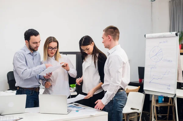 Beyin fırtınası. Zeki iş adamlarından oluşan neşeli bir grup dizüstü bilgisayara bakıp gülümsüyor.