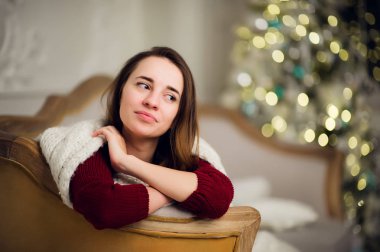 Gülümseyen güzel kadın Noel ağacı üzerinde arka plan üzerinde oturan