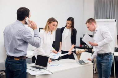 Toplantı ve dizüstü bilgisayarlar kullanarak evraklarla tartışılması sırasında ofisinde oturan genç iş adamları