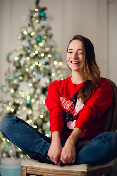 幸せな若いです女性座ってクリスマスツリー近く. — ストック写真
