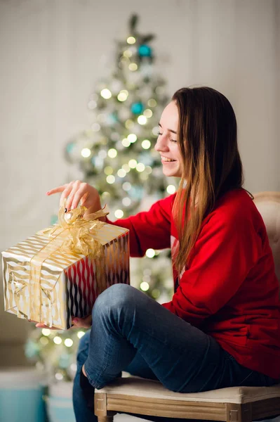 家でクリスマスツリーに座って贈り物と美しい女性の肖像 — ストック写真