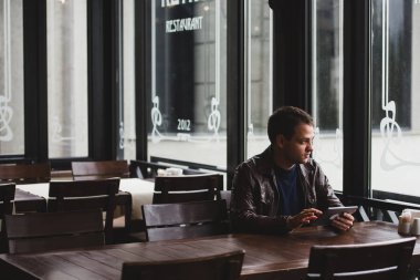 Genç adam ya da kafede tablet bilgisayar kullanarak öğrenci