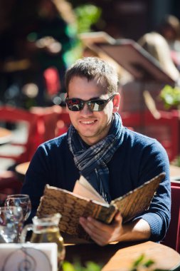 Serin genç adam bir şey bir sokak café'de sipariş güneş gözlüğü