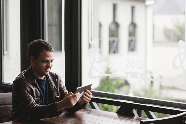 Νεαρός άνδρας κάθεται στο city café κατά την ώρα του μεσημεριανού και εργασίας στο tablet — Φωτογραφία Αρχείου