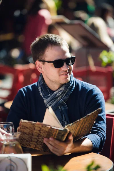 Joven guay en gafas de sol pidiendo algo en un café de la calle — Foto de Stock