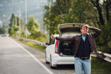 Otostop - bir sürücü gerekir. Genç adam eliyle arabanın önüne kaldırdı yolda