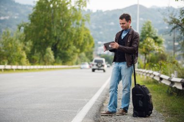 adam araba veya taksi bekliyor dijital tablet ile ayakta. Otostop