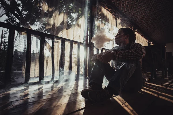 Vaping joven hombre produce vapor en la silueta de la puesta del sol — Foto de Stock