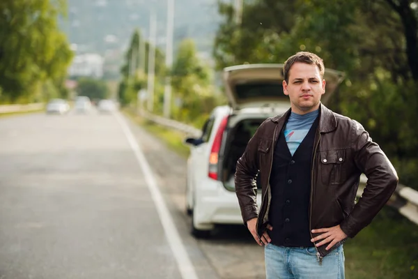 Autoestop - Necesita un paseo. Joven en la carretera con la mano levantada delante del coche — Foto de Stock