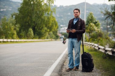 adam araba veya taksi bekliyor dijital tablet ile ayakta. Otostop