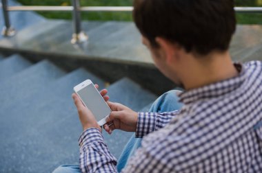 Bir merdiven üzerinde oturan yakın çekim mobil akıllı telefonunu açık adam kullanır