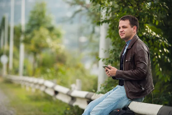 Hombre sentado en una valla de carretera con la tableta GPS PC y el uso de mapas en línea — Foto de Stock