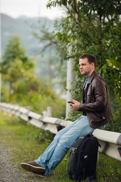 Человек, сидящий на дорожном заборе с GPS планшетного ПК и с помощью онлайн-карт — стоковое фото