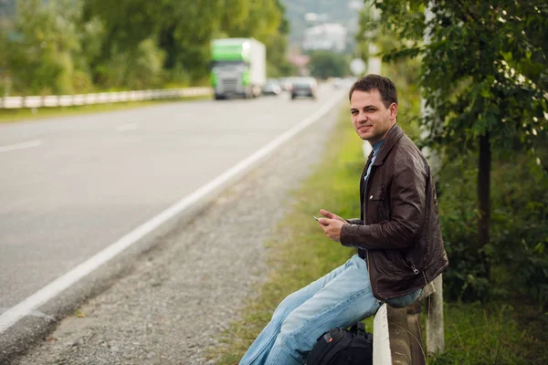 Чоловік сидить на дорожньому паркані з планшетом gps і використовує онлайн-карти — стокове фото