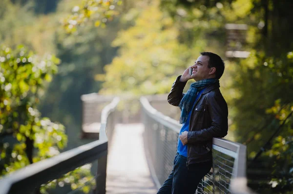 Кавказский мужчина с мобильным телефоном делает звонок в красивом месте в природном парке на открытом воздухе — стоковое фото