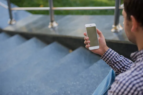 Mann benutzt sein Handy im Freien, während er auf einer Treppe sitzt, Nahaufnahme — Stockfoto